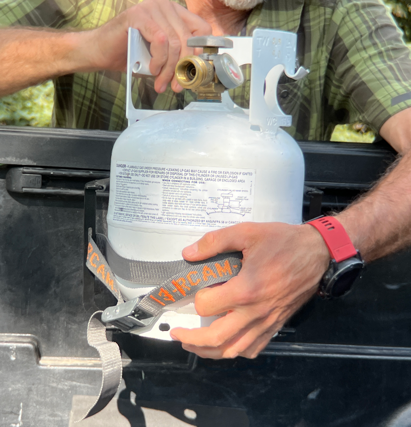 Installing Propane Tank, which does not come with the bracket, into the bracket and cam strap.