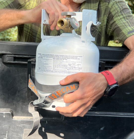 Installing Propane Tank, which does not come with the bracket, into the bracket and cam strap. 